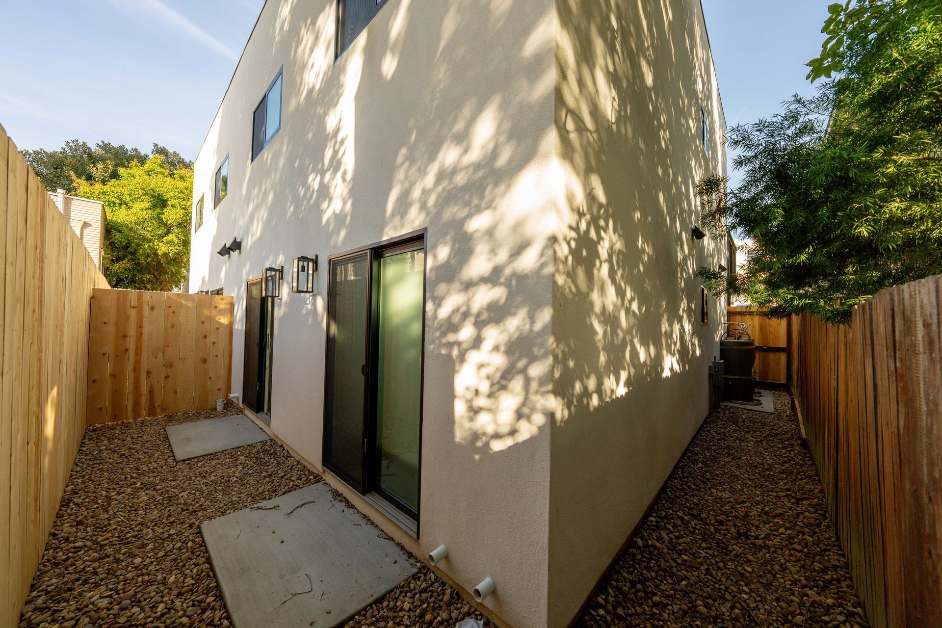 The backyard of a house with a wooden fence and gravel.