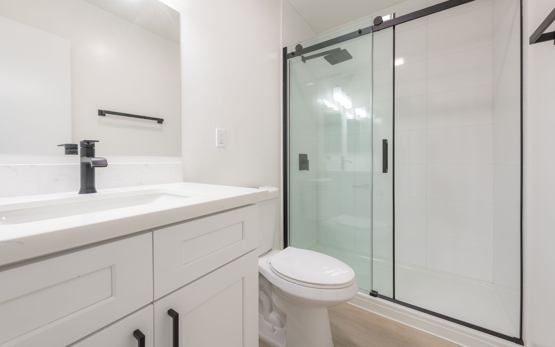A bathroom with a toilet , sink , mirror and shower stall.