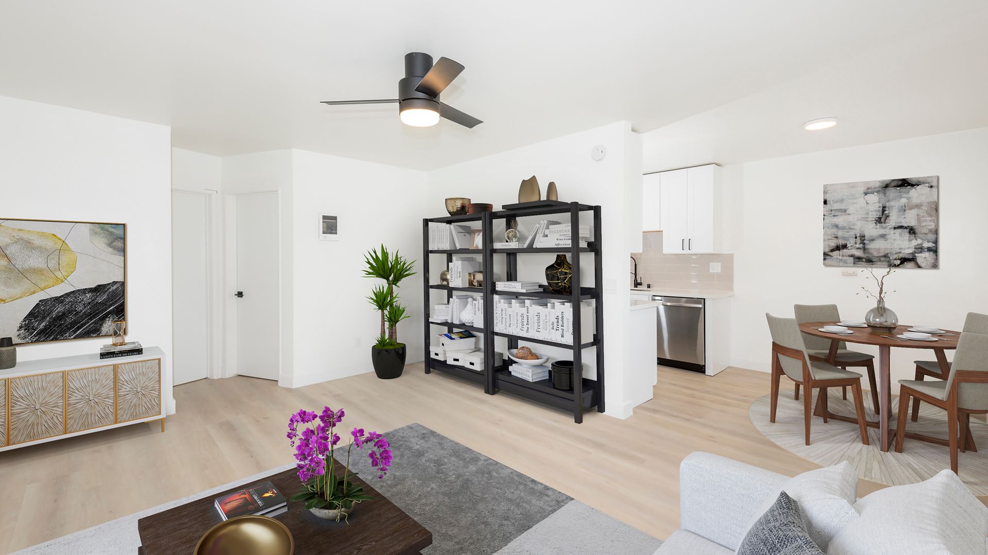 A living room with a couch , table , chairs and a ceiling fan.