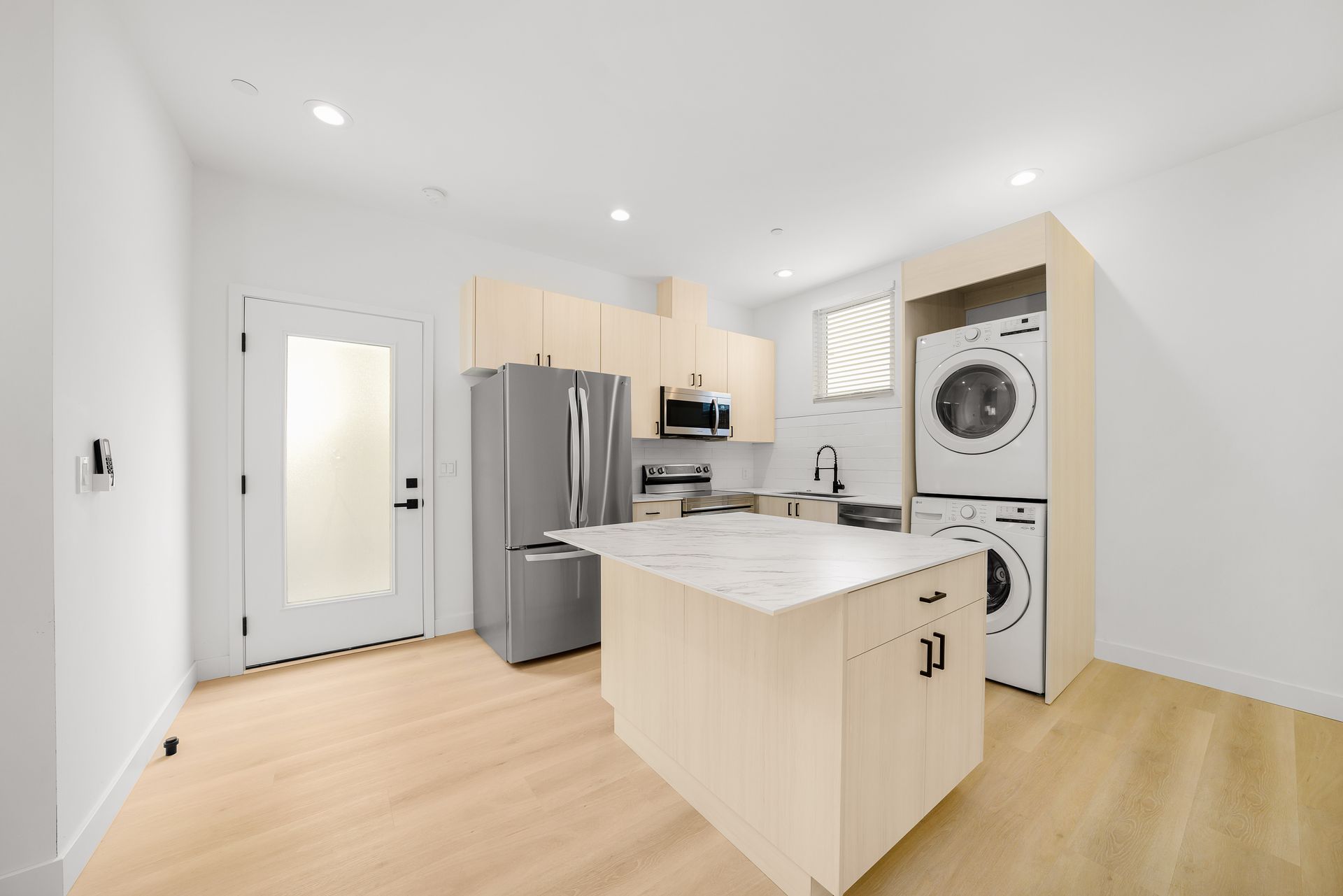A kitchen with a refrigerator , washer and dryer stacked on top of each other.