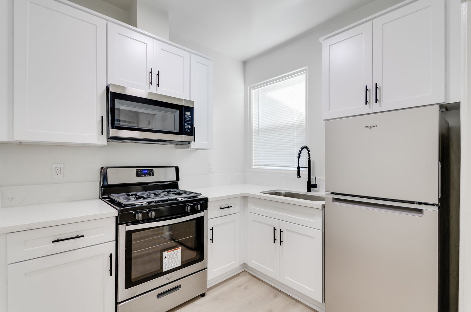 A kitchen with stainless steel appliances and white cabinets.
