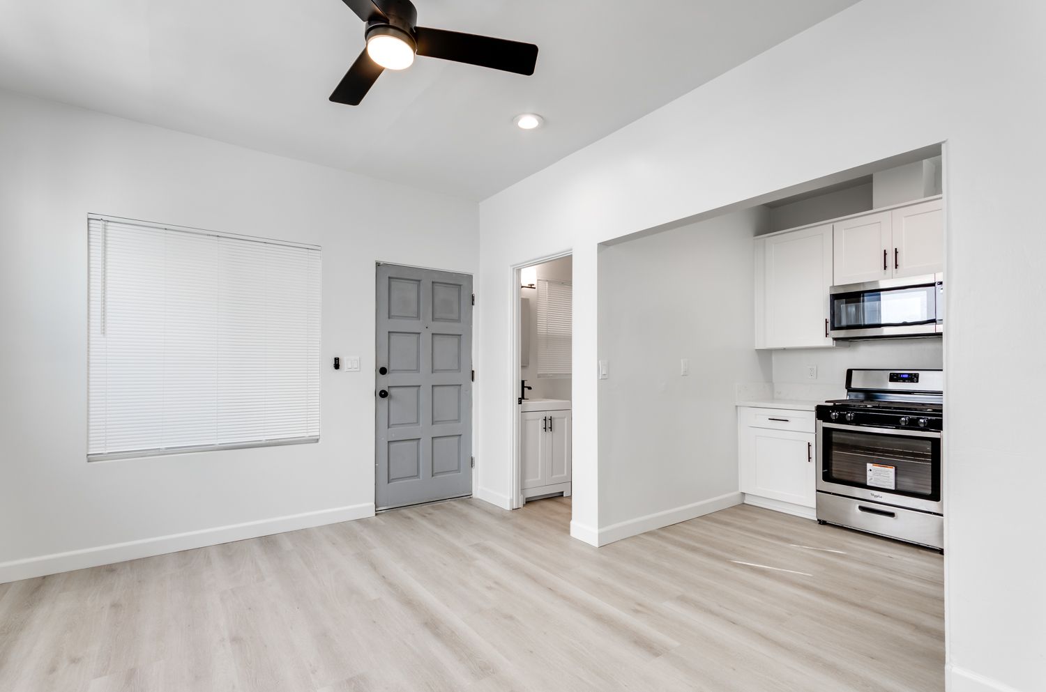 An empty apartment with a kitchen and a ceiling fan