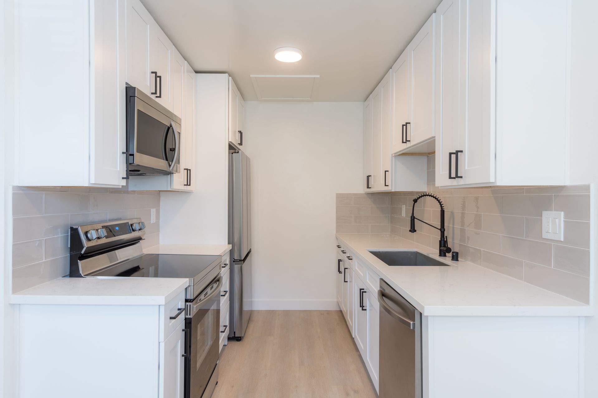 A kitchen with white cabinets , stainless steel appliances and a sink.