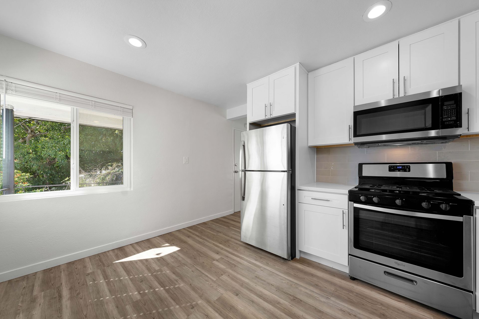 An empty kitchen with stainless steel appliances and white cabinets.