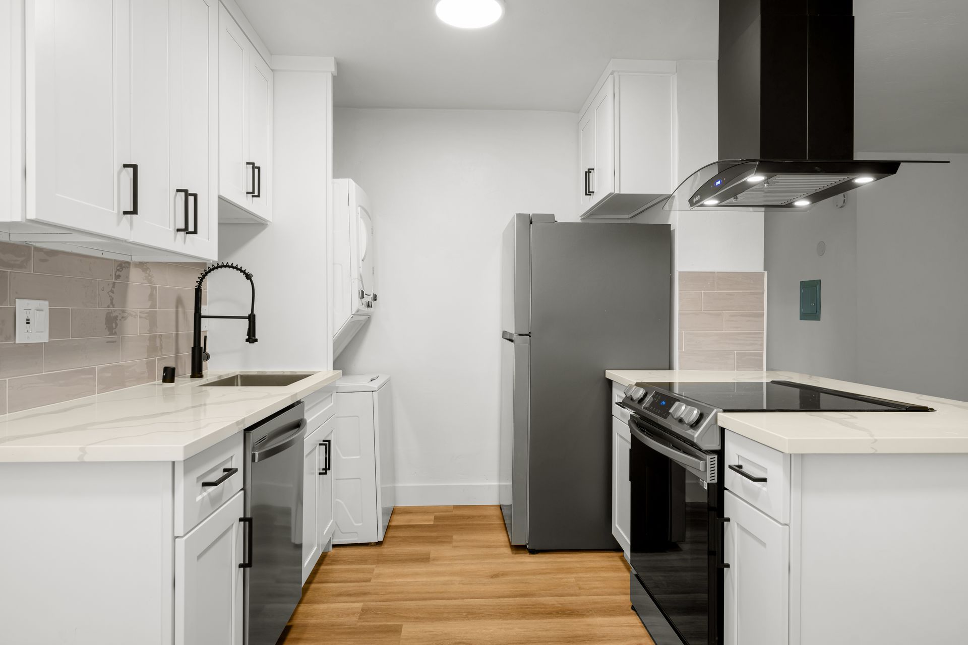 A kitchen with white cabinets , stainless steel appliances , a refrigerator , stove , sink and dishwasher.
