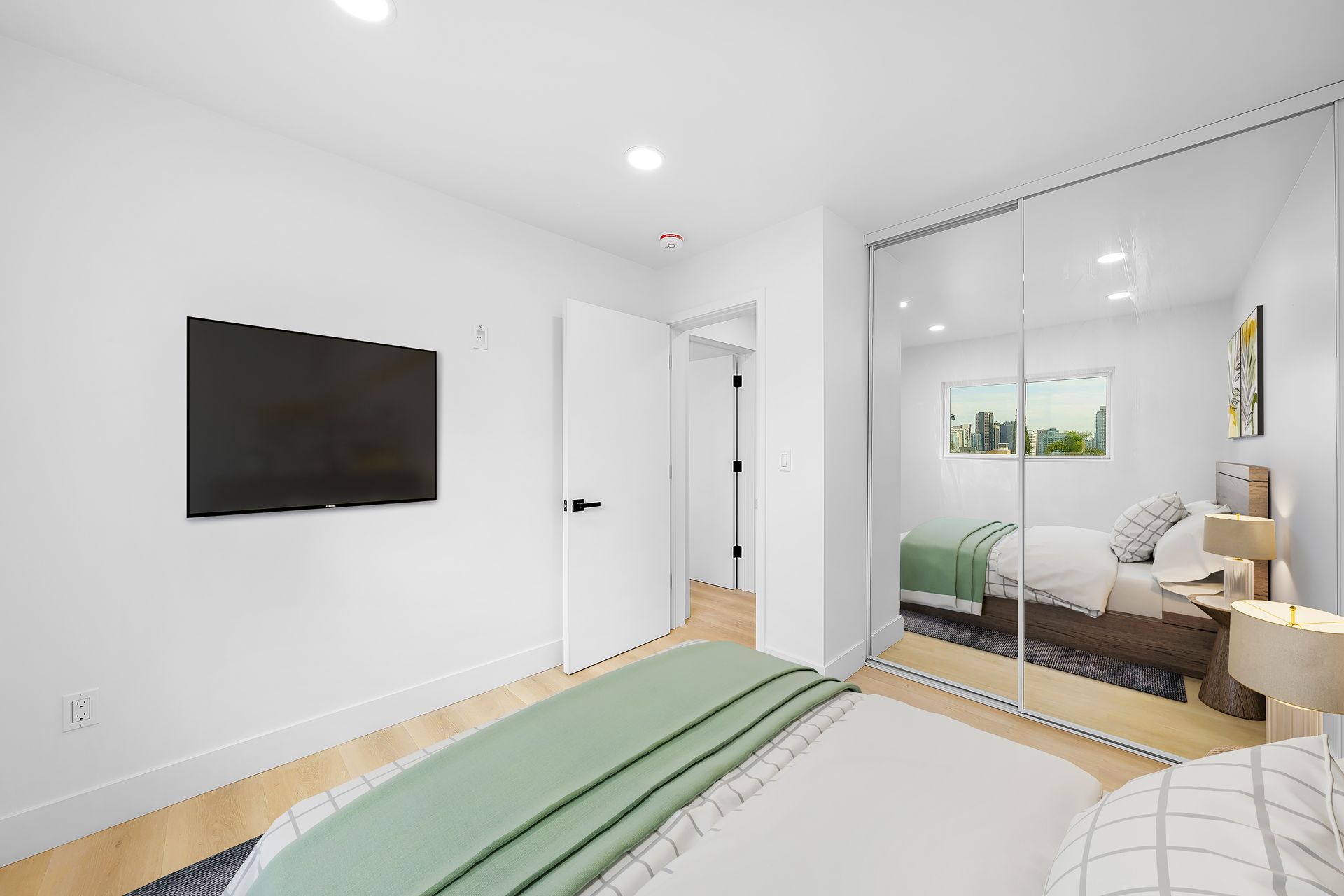 A bedroom with a bed , television , and mirrored walls.