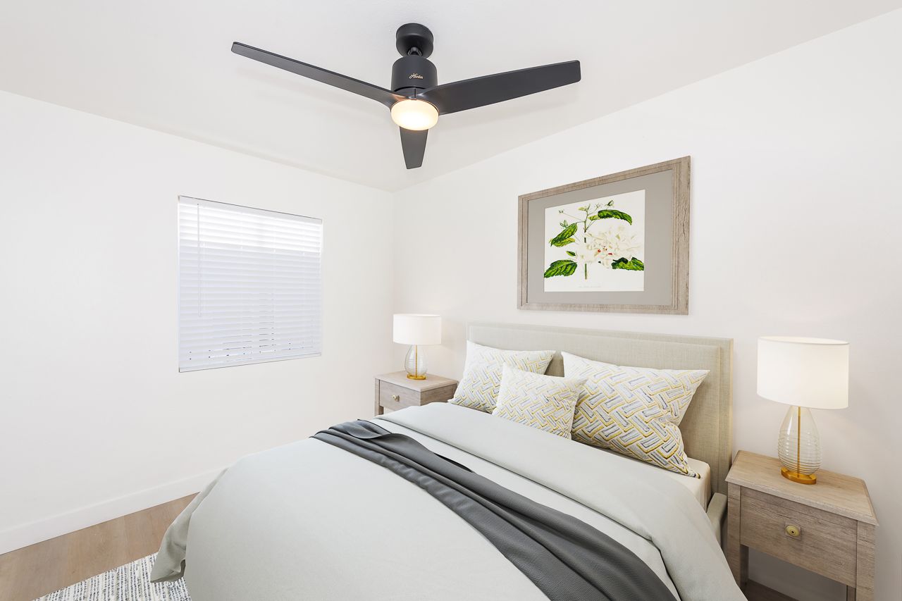 A bedroom with a bed , nightstands , lamps and a ceiling fan.