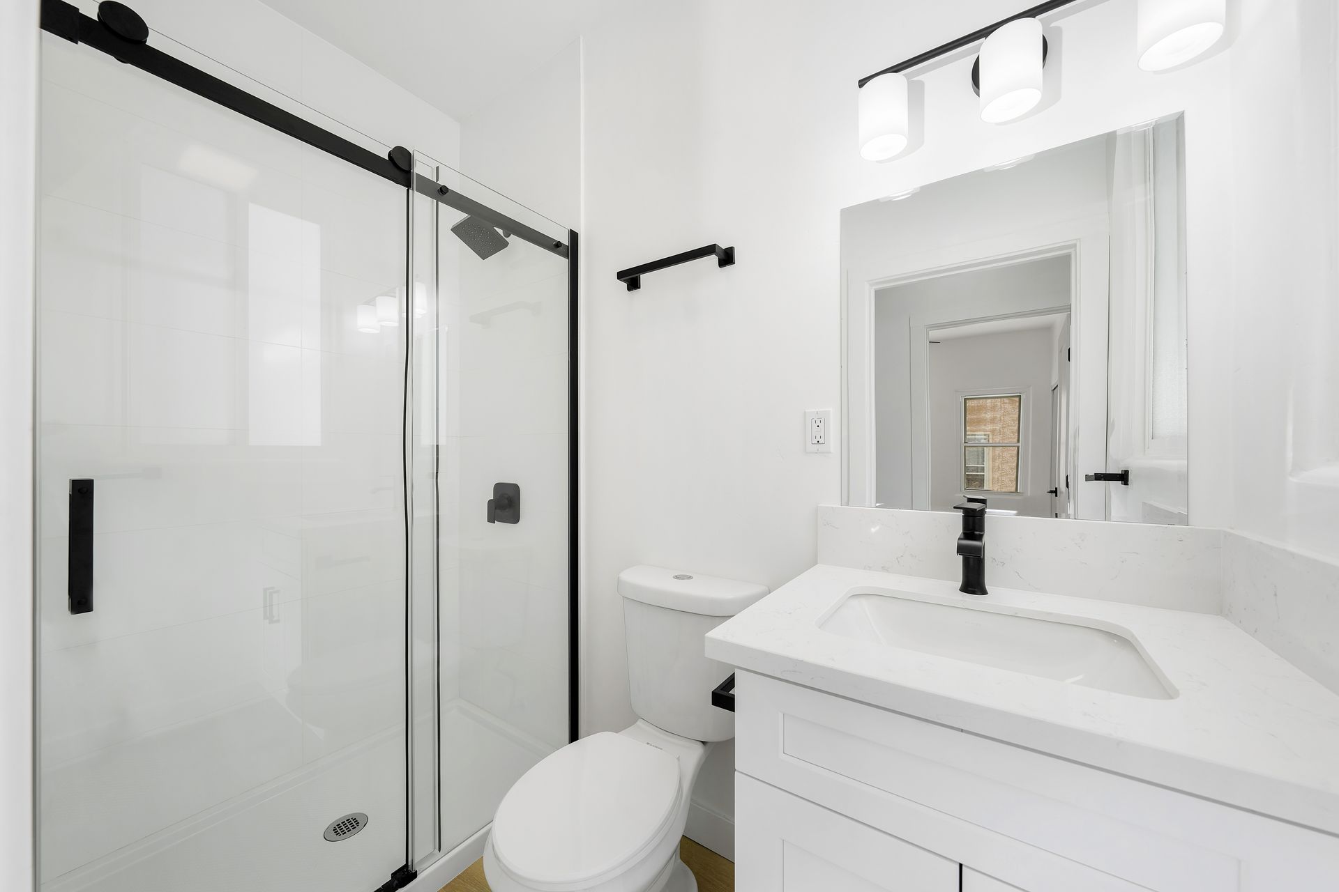 A bathroom with a toilet , sink , shower and mirror.