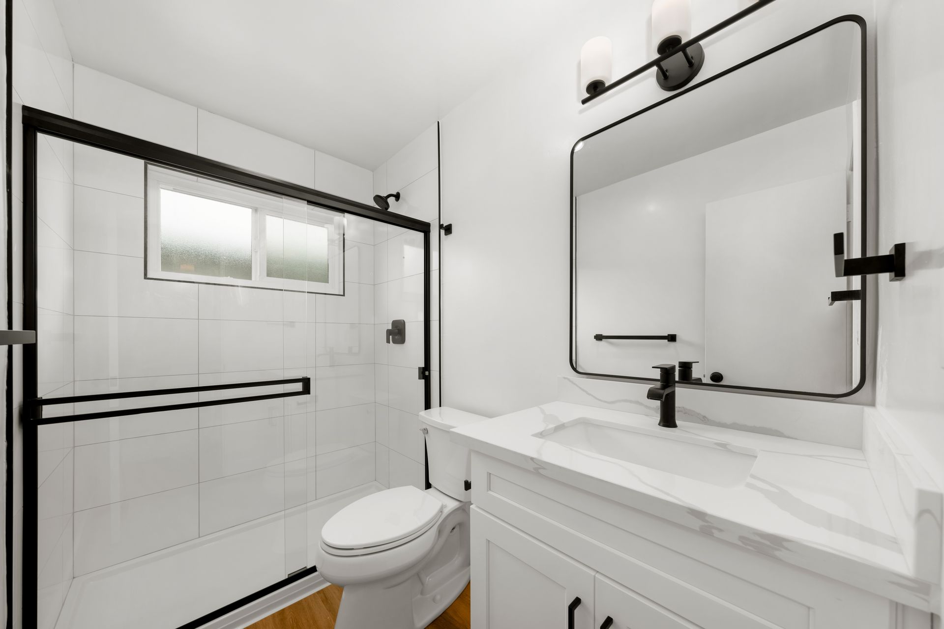 A bathroom with a toilet , sink , shower and mirror.