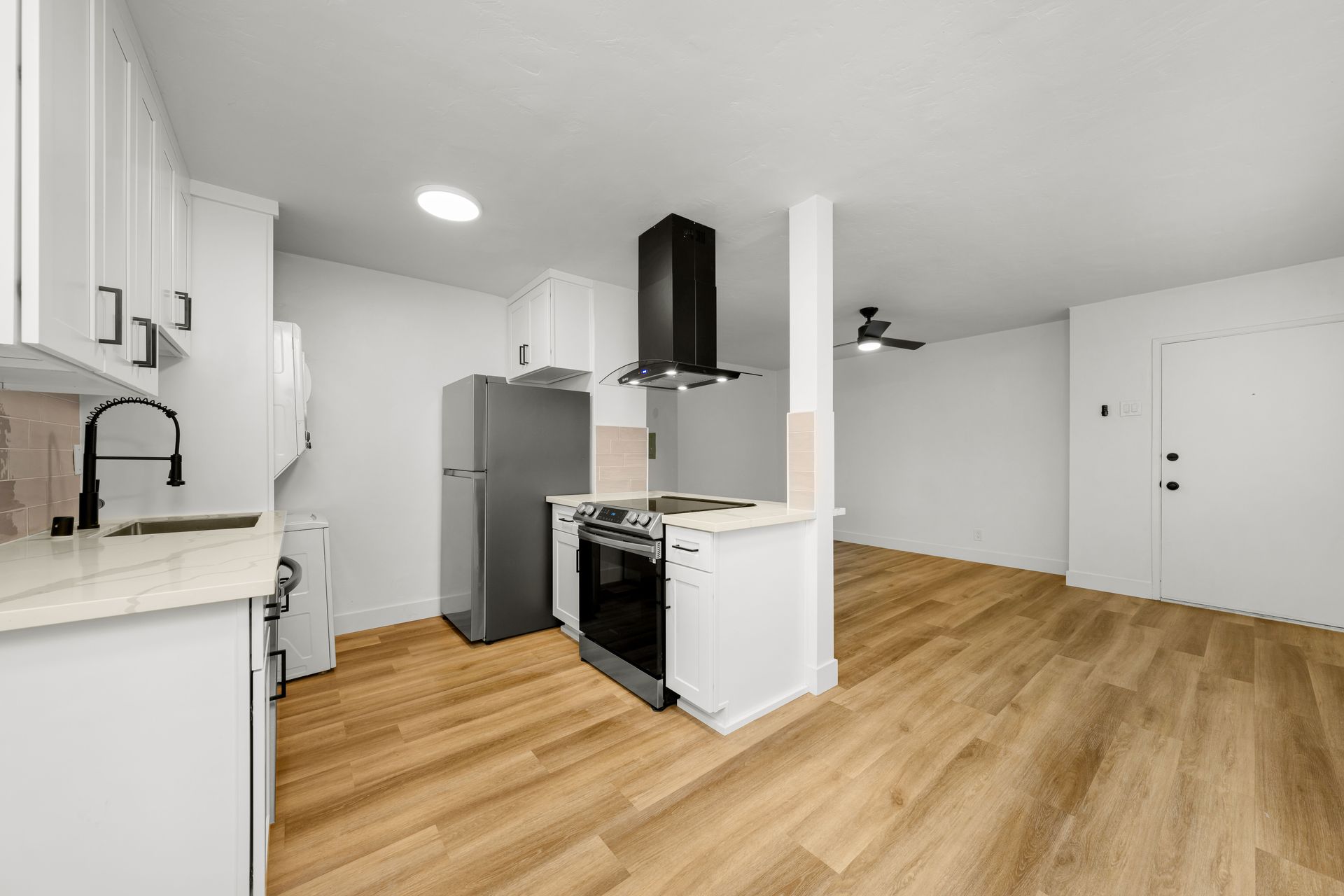 A kitchen with a refrigerator , stove , sink and ceiling fan.