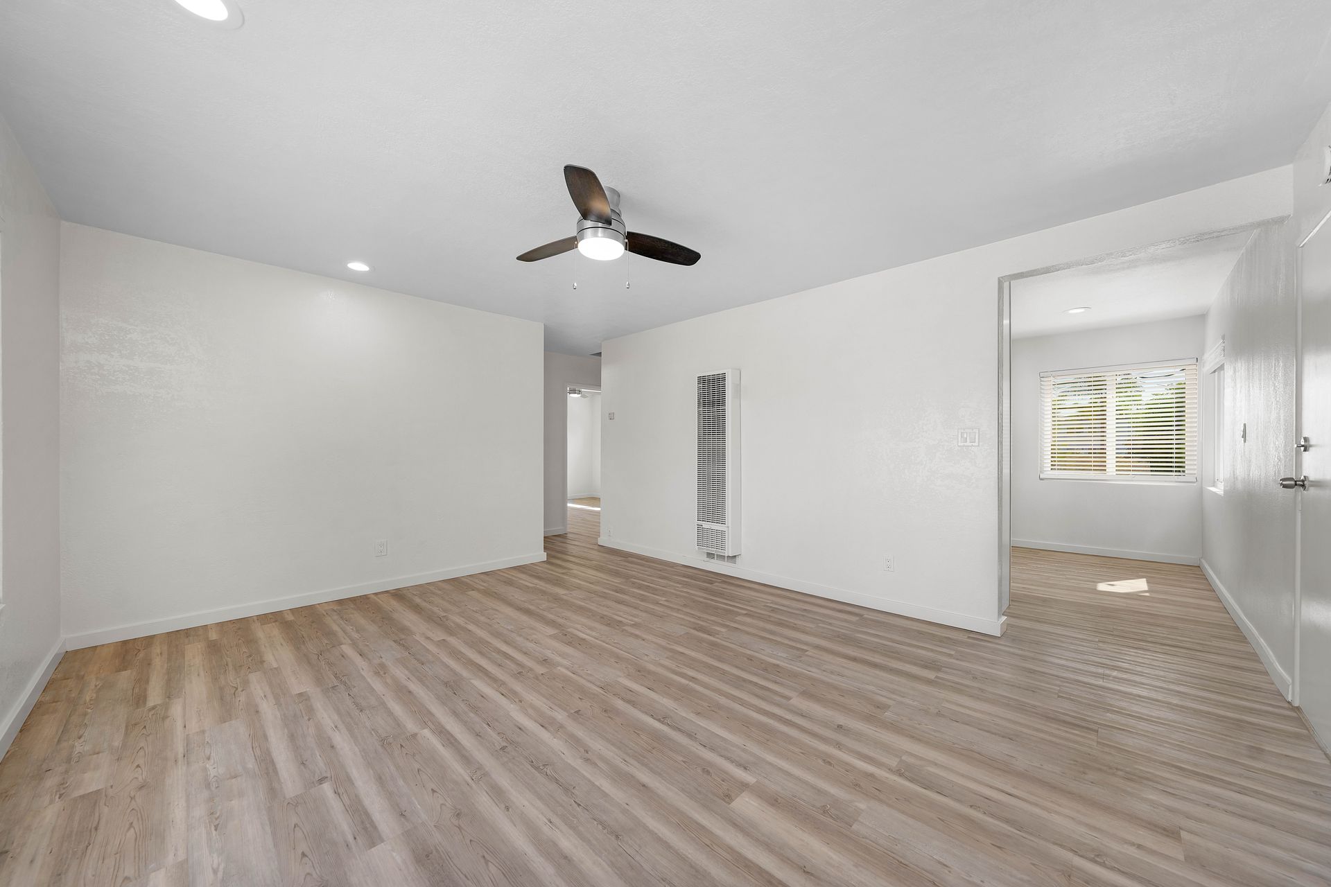 An empty living room with hardwood floors and a ceiling fan.