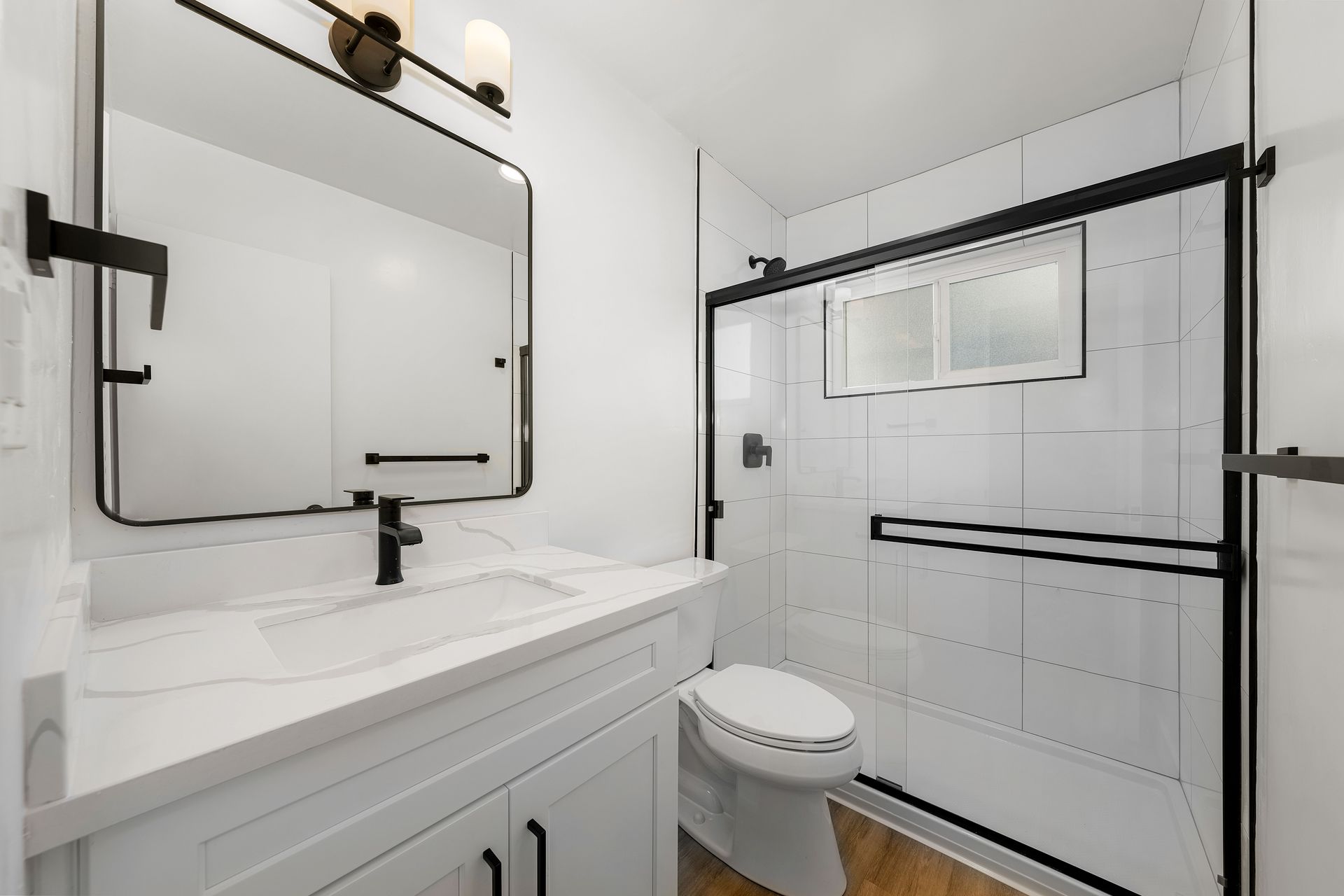 A bathroom with a toilet , sink , mirror and shower.