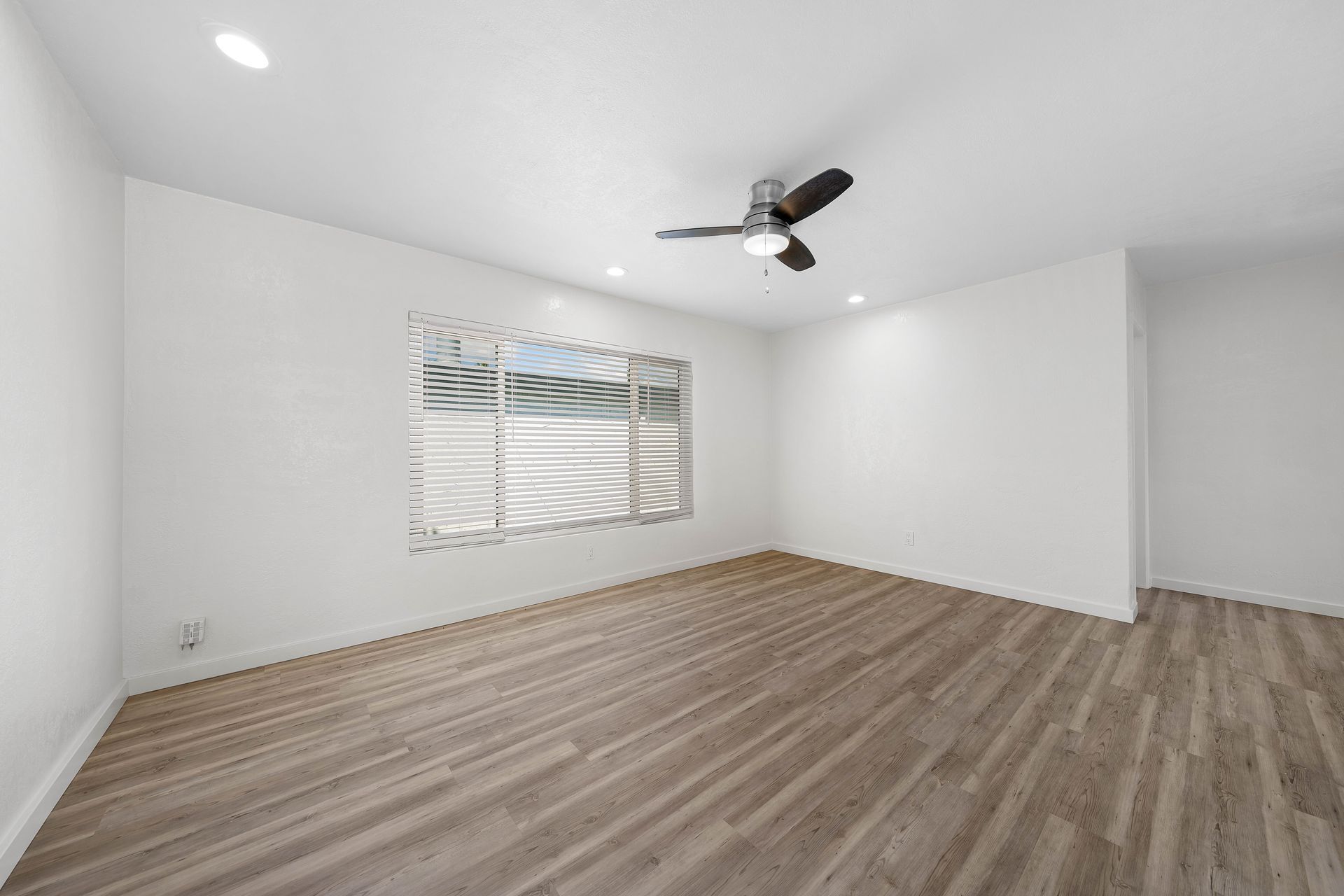 An empty room with hardwood floors and a ceiling fan.