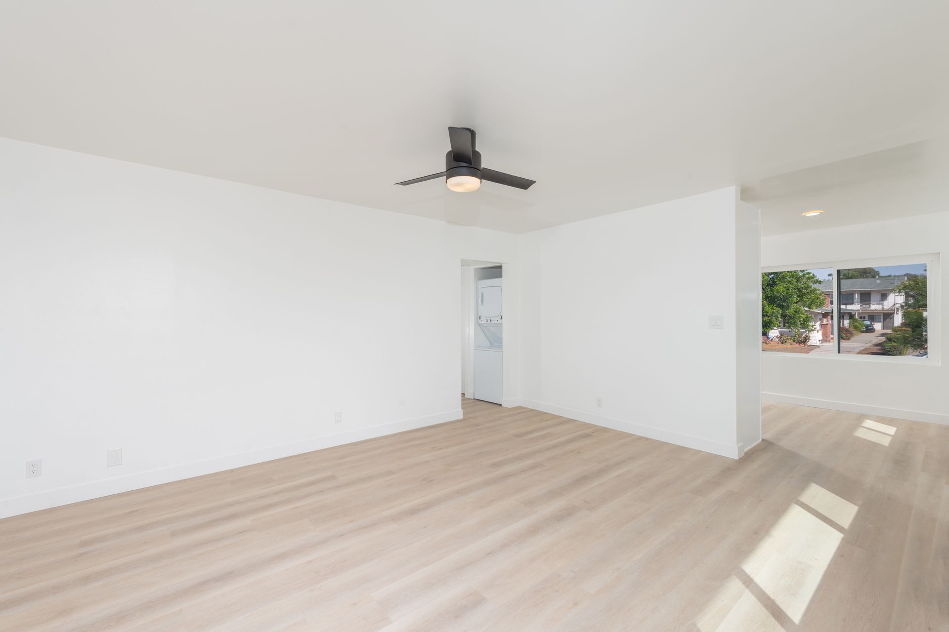 An empty living room with hardwood floors and a ceiling fan.