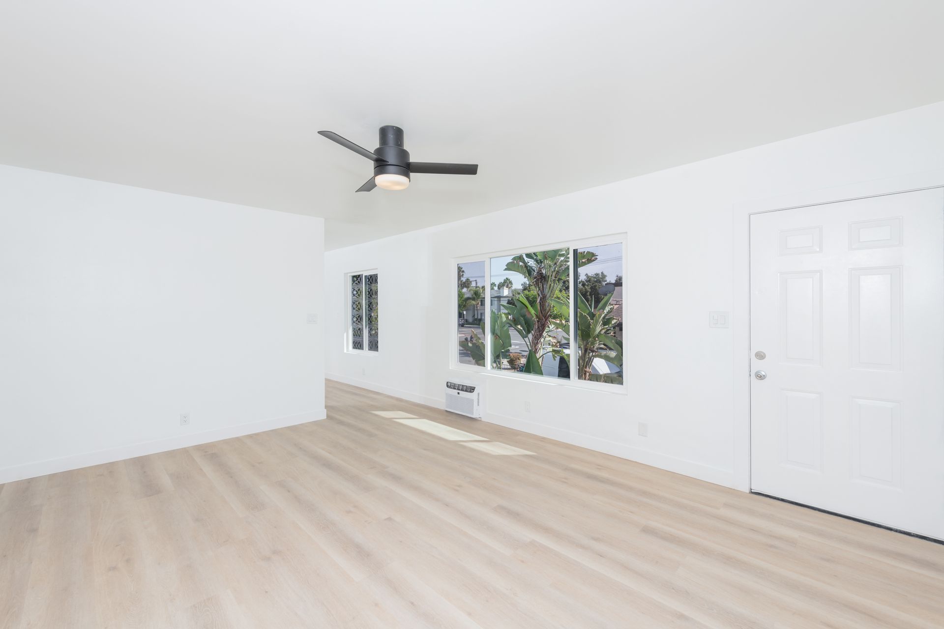 An empty living room with hardwood floors and a ceiling fan.