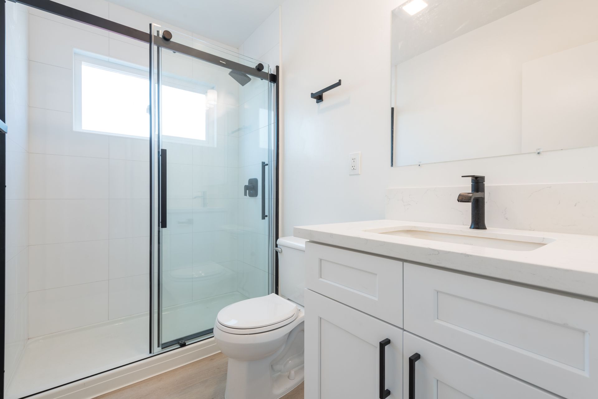 A bathroom with a toilet , sink and shower with sliding glass doors.
