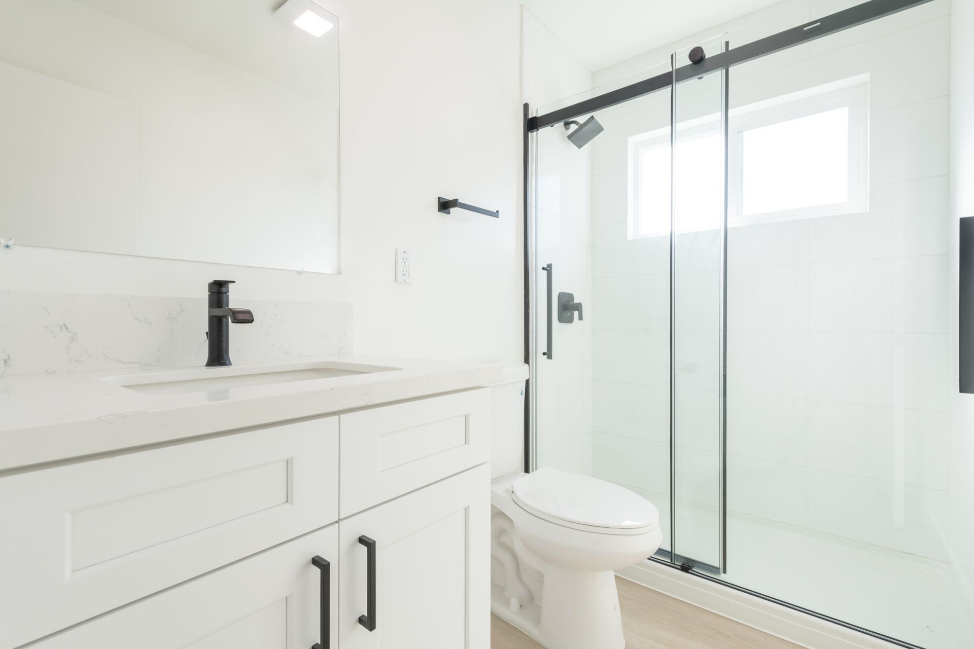 A bathroom with a toilet , sink , mirror and sliding glass shower door.