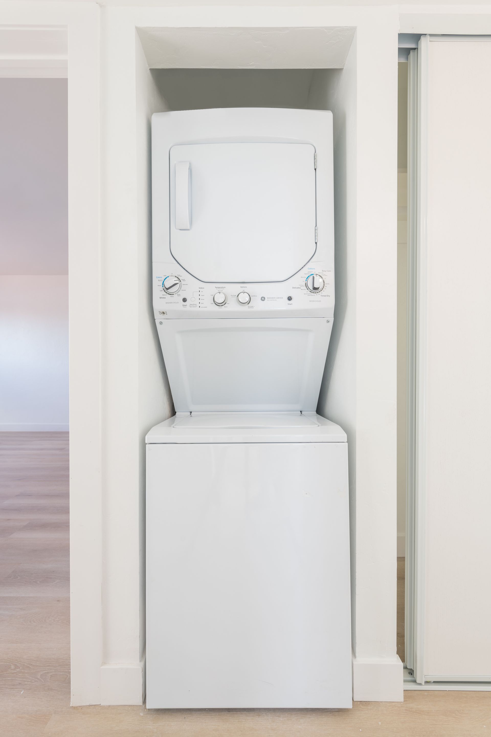 A white washer and dryer are stacked on top of each other in a closet.