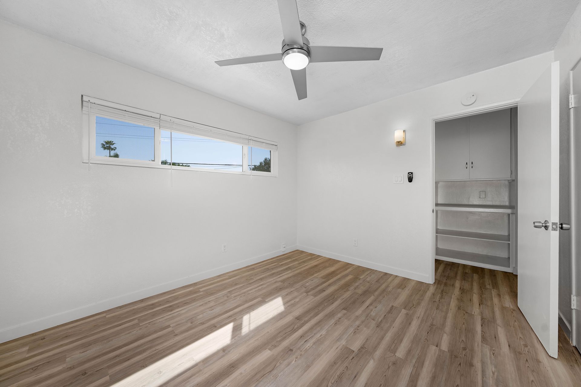 An empty bedroom with hardwood floors and a ceiling fan.