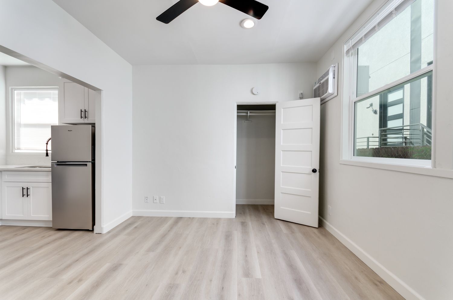 An empty room with a refrigerator and a ceiling fan.