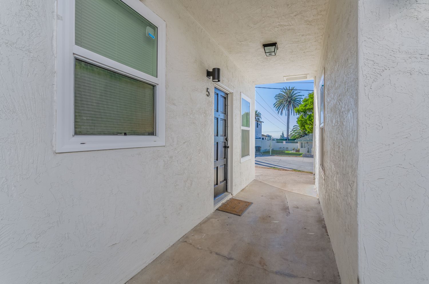 A white house with a concrete walkway leading to the front door.