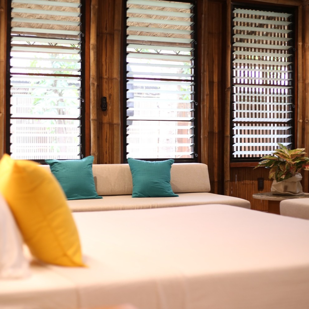 A bedroom with a bed, two gray pillows, one patterned pillow, two round wall art pieces, and a lamp on a small side table.
