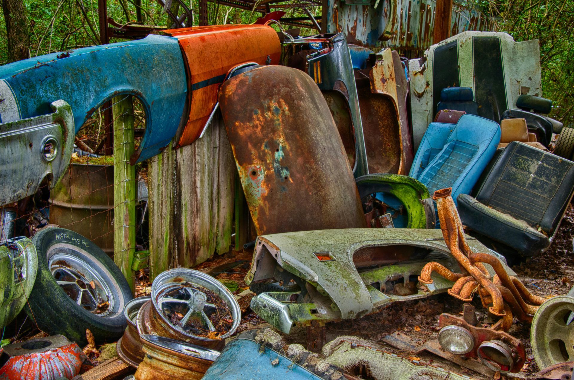 Scrap metal pile: rusted car parts in shades of orange, blue, and brown.