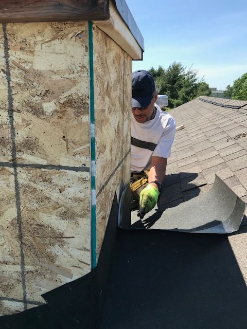 A man wearing green gloves is working on a roof
