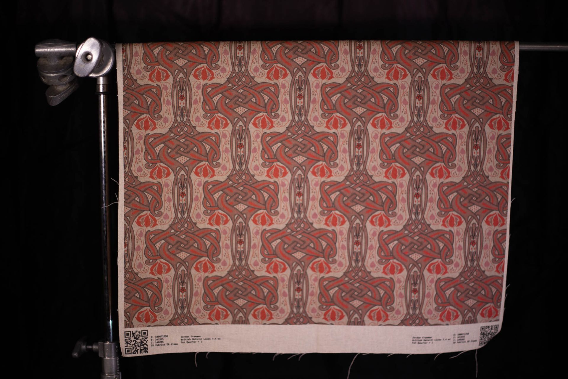 A piece of fabric with a pattern on it is hanging on a stand.
