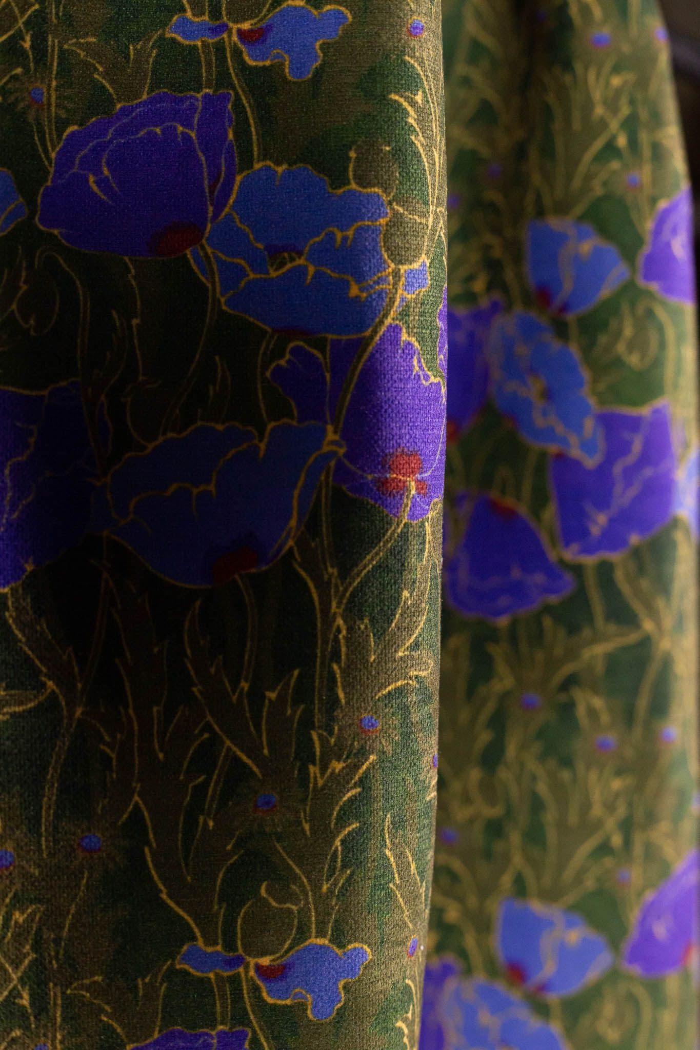 A close up of a green fabric with purple flowers on it.