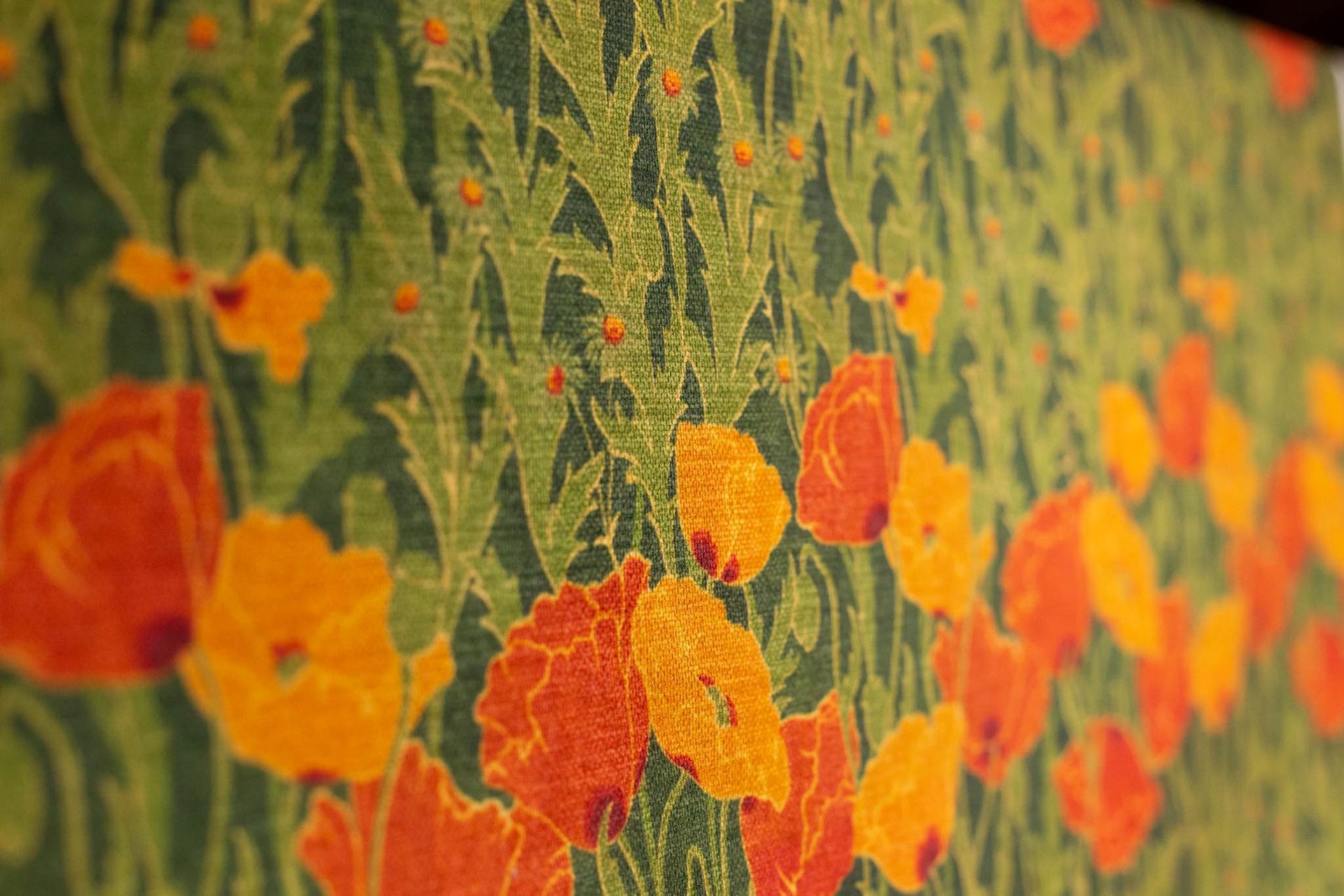 A close up of a green and orange fabric with flowers on it.