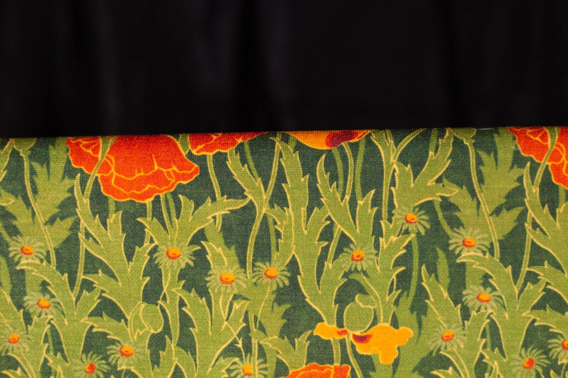 A close up of a green and orange floral pattern on a black background.