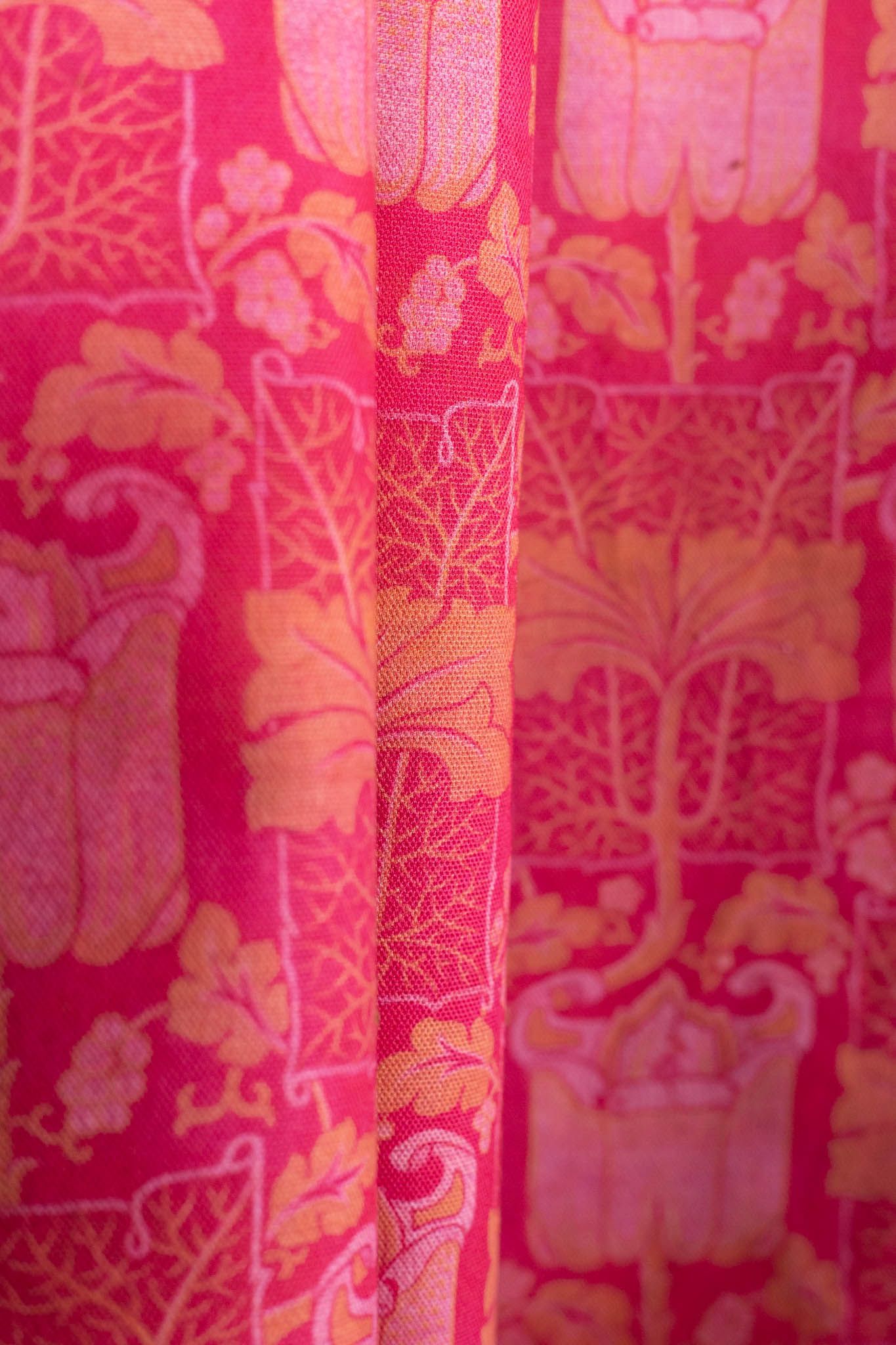 A close up of a pink and yellow curtain with a pattern on it.