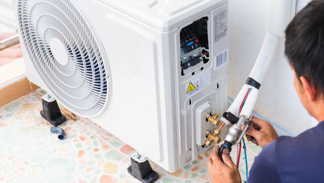 A man is working on an air conditioner in a room.