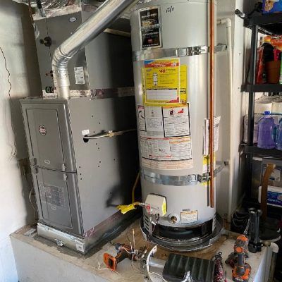 A water heater is sitting next to a furnace in a room.