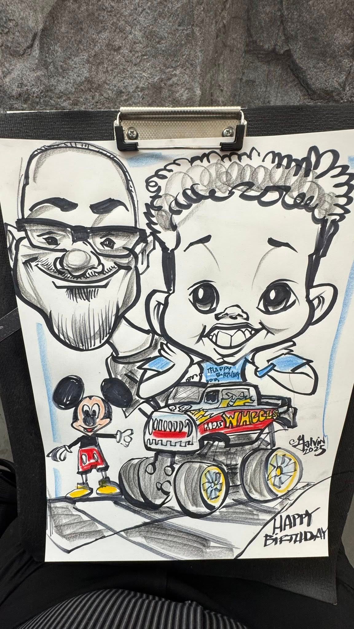Cartoon drawing of two smiling faces and a small Mickey Mouse figure on a clipboard, with colorful wheels below.