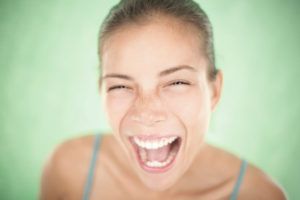 A close up of a woman laughing with her mouth open.