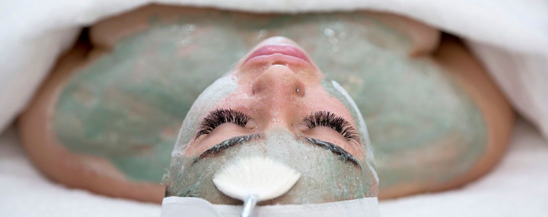 A woman is getting a facial treatment with a mask on her face.