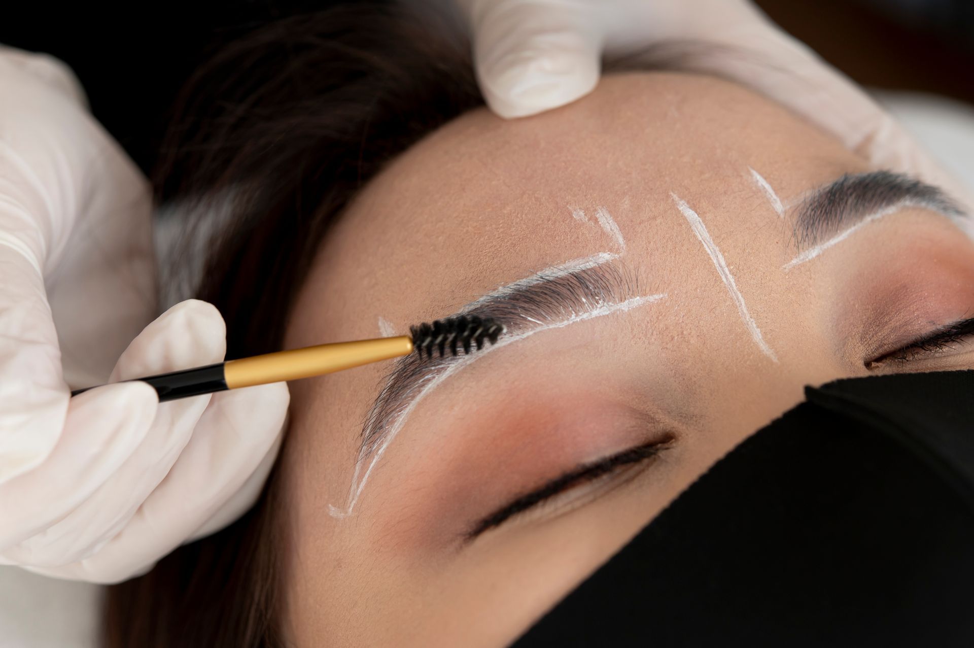 A woman is getting her eyebrows painted with a brush.