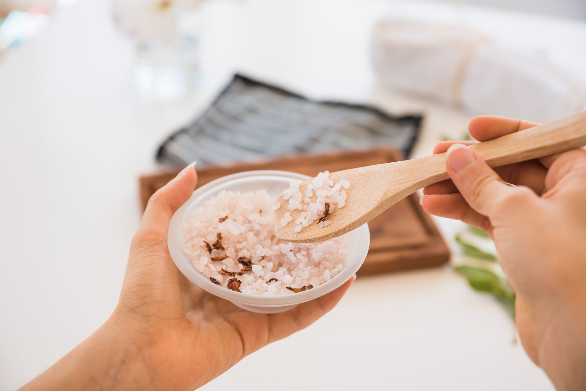 A person is holding a bowl of salt and a wooden spoon.