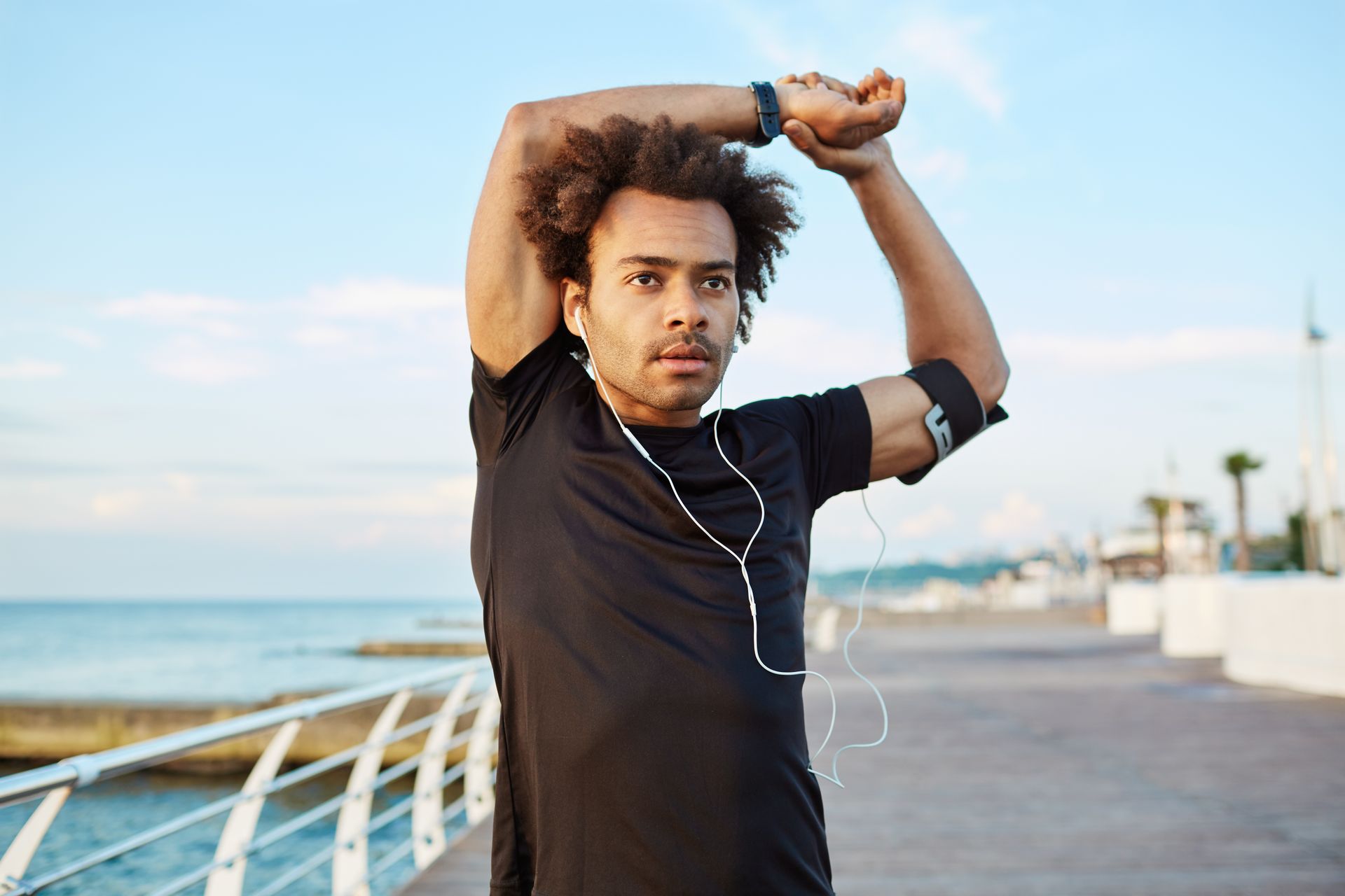 A man is stretching his arms on a pier near the ocean.