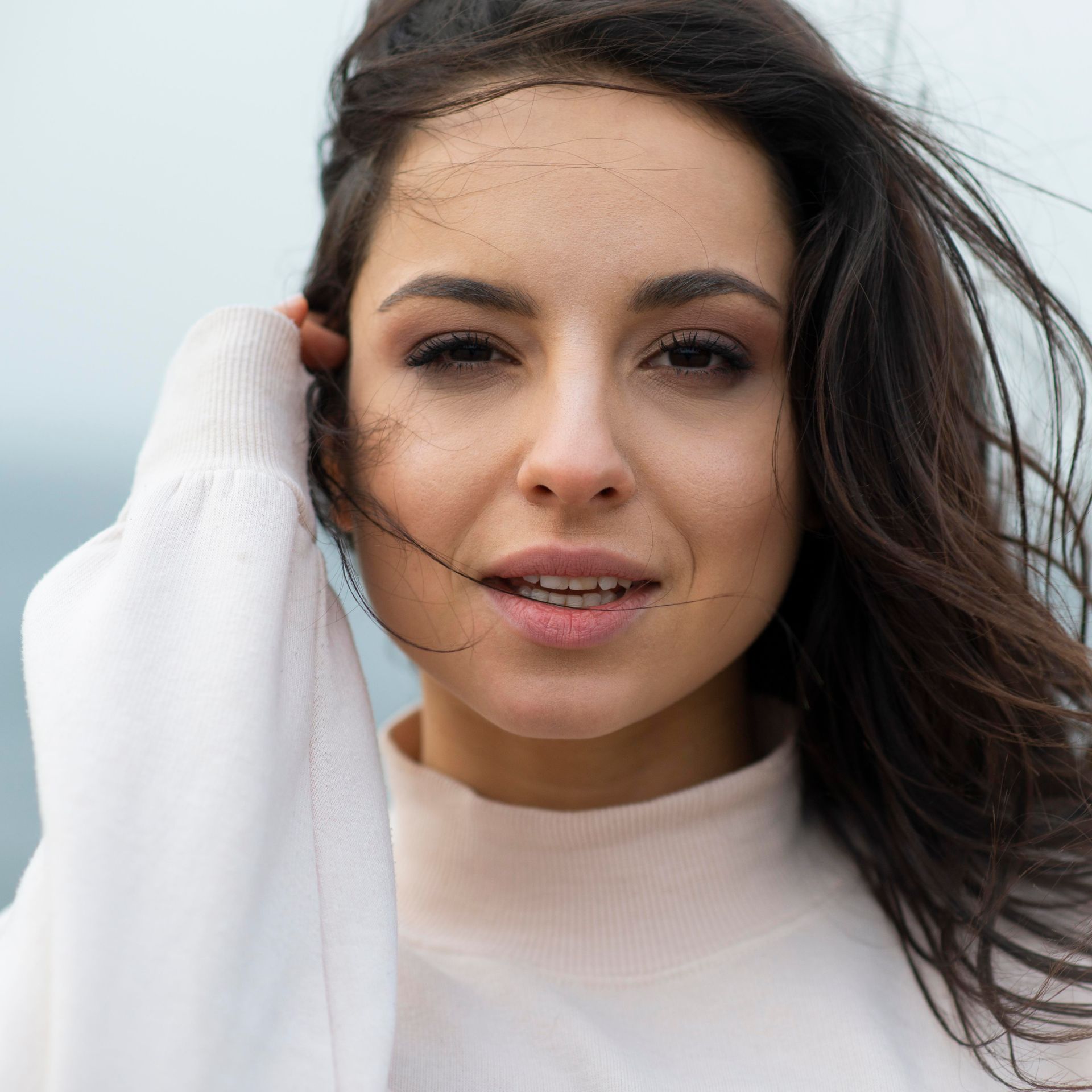 A close up of a woman 's face with her hair blowing in the wind.