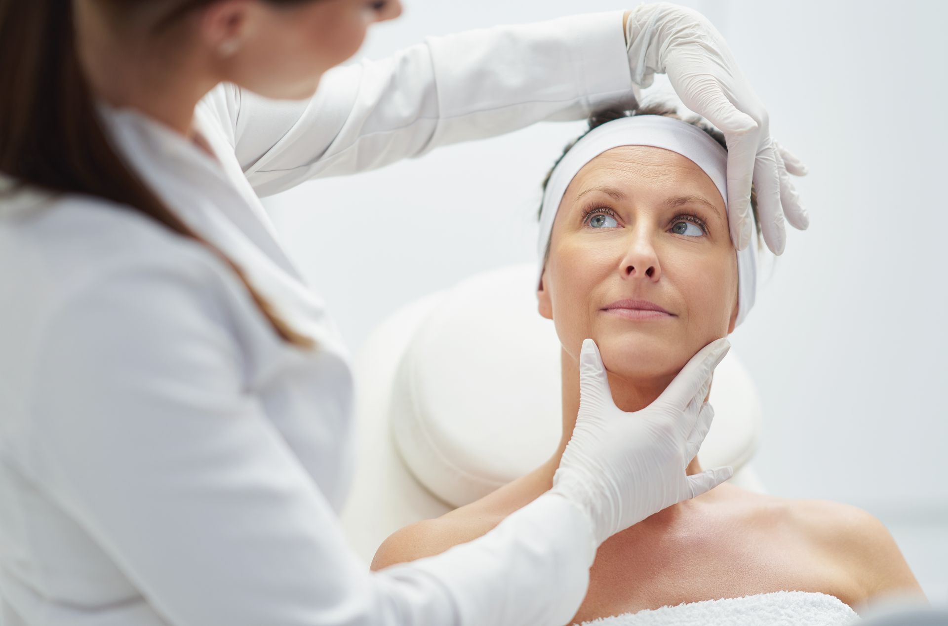 A woman is getting her face examined by a doctor.