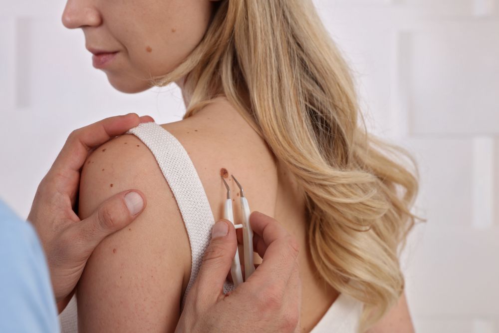 A doctor examines a woman's shoulder with small medical instruments.