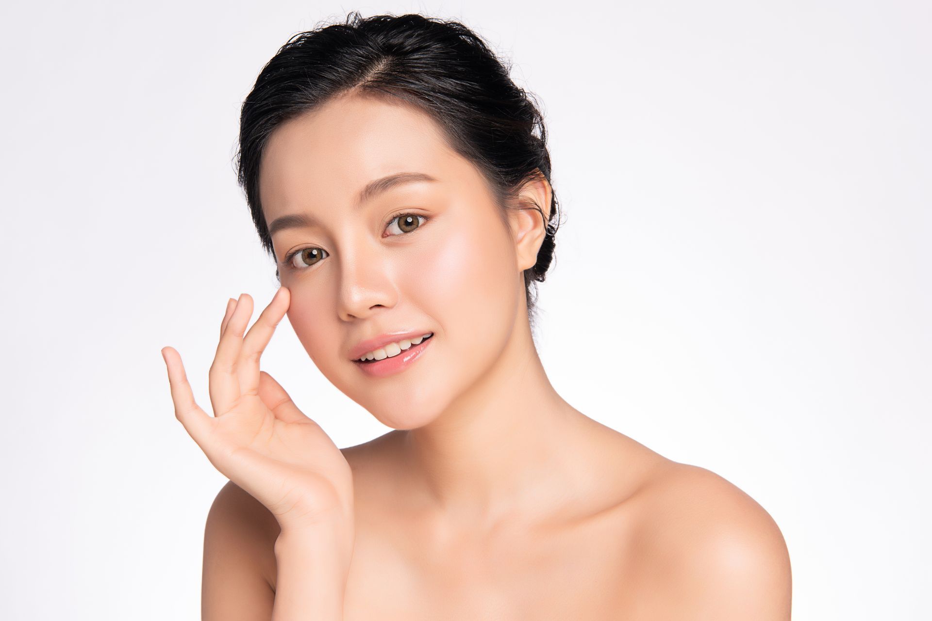 A woman is touching her face with her hand and smiling.