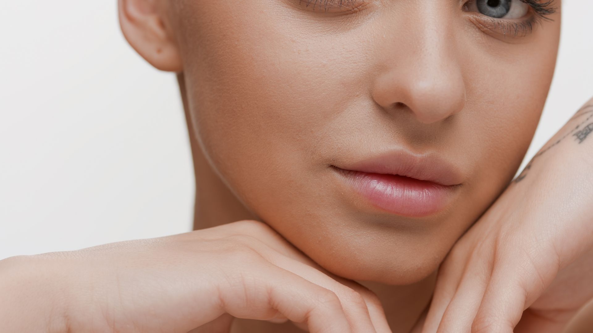 A close up of a woman 's face with her hands on her chin.