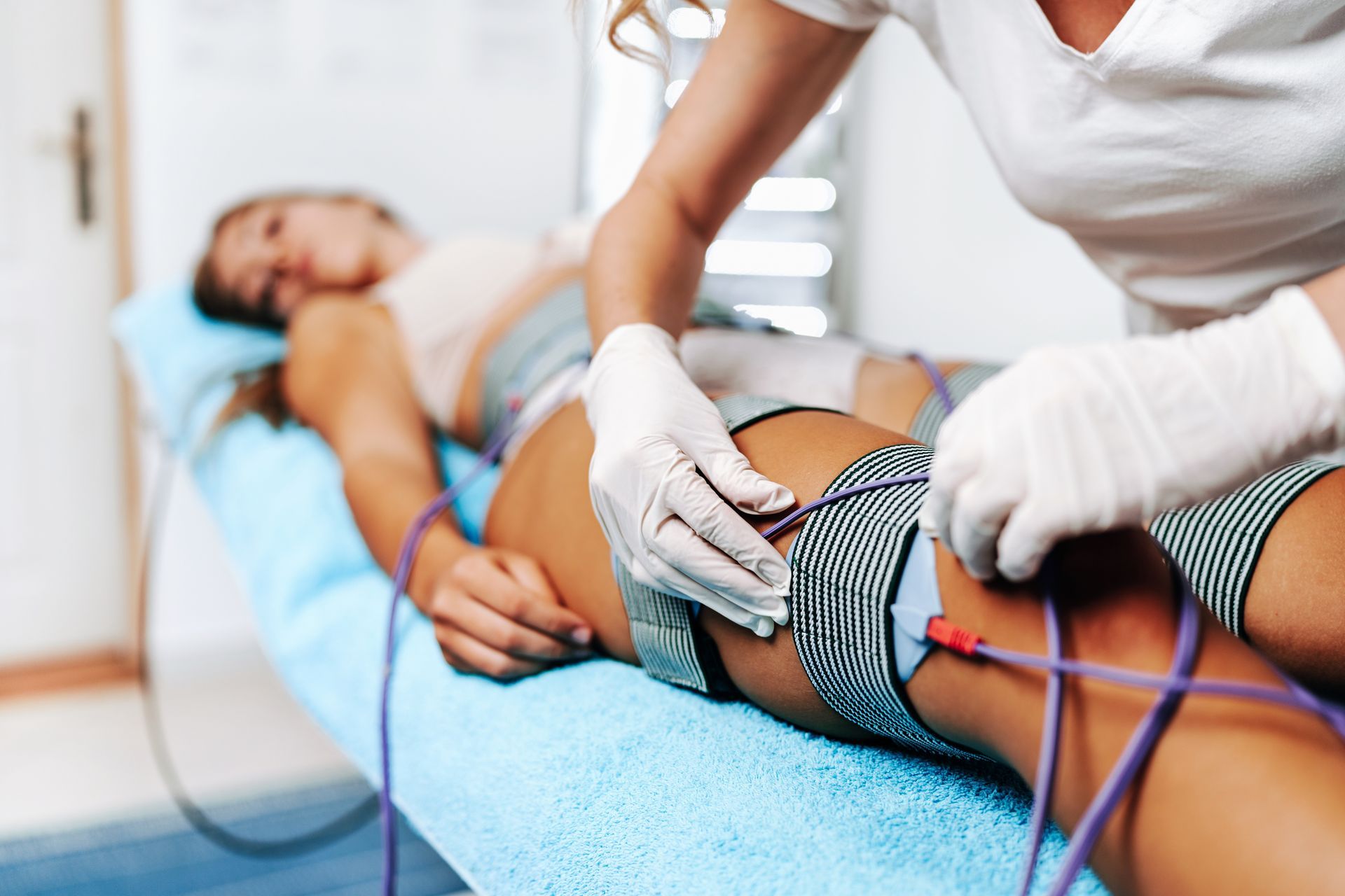 A woman is getting an electrotherapy treatment on her legs.