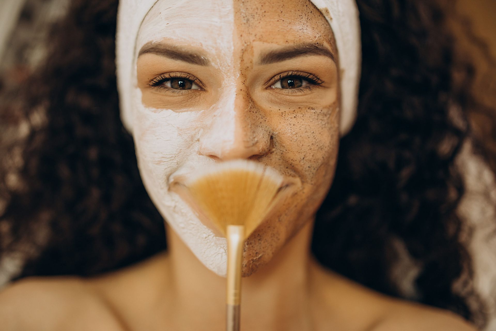 A woman is applying a mask to her face with a brush.