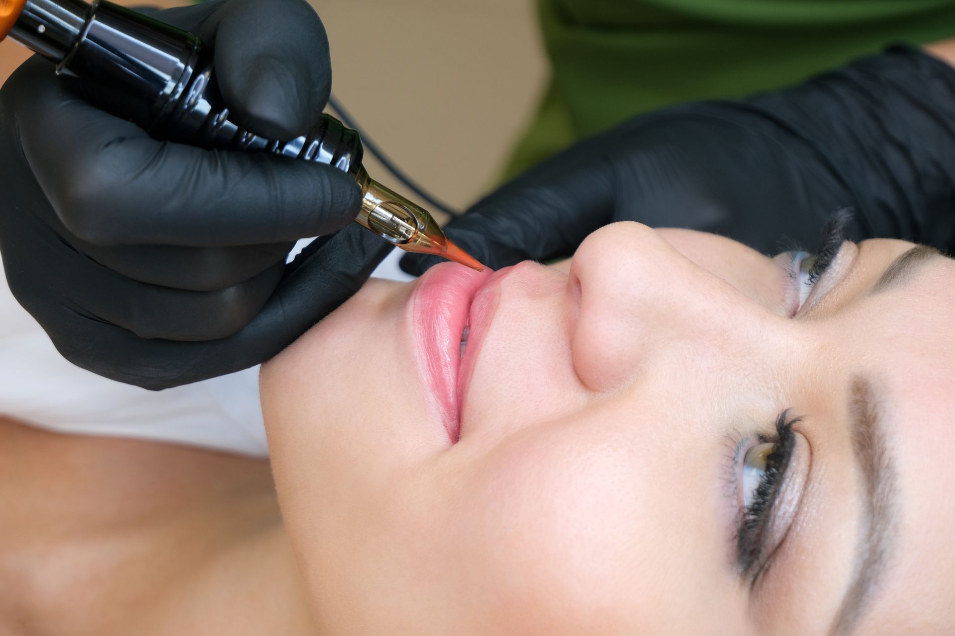 A woman is getting a permanent makeup tattoo on her lips.