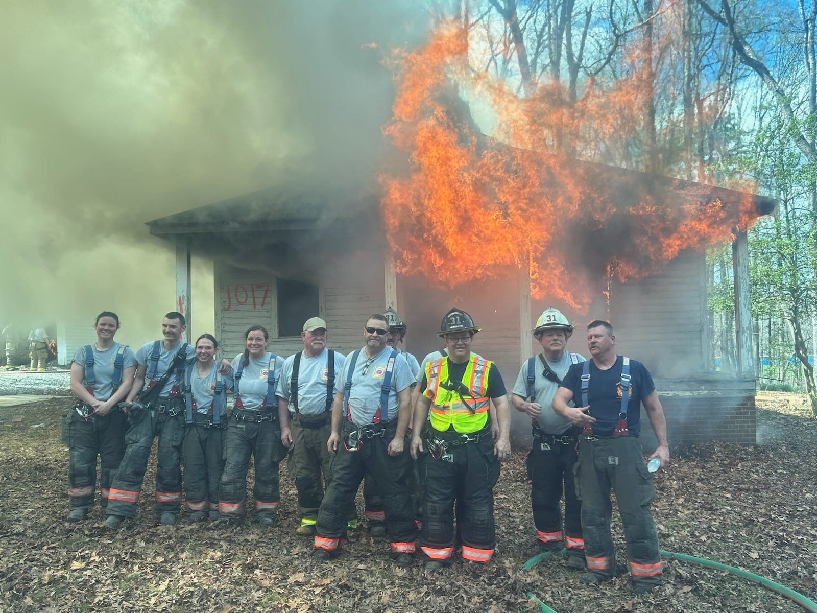 A group of firemen standing in front of a burning structure